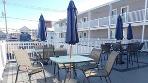 Une terrasse dotée de mobilier d’extérieur, notamment des tables, des chaises et des parasols.