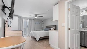 Une chambre à coucher avec un lit, une table de chevet et un ventilateur de plafond.