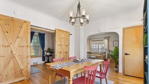 Uma sala de jantar com uma mesa de madeira, cadeiras vermelhas e um candelabro.