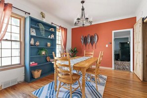 A dining area with a wooden table and chairs, a blue bookshelf, and a red accent wall. - The Stillwater Retreat (Stillwater)