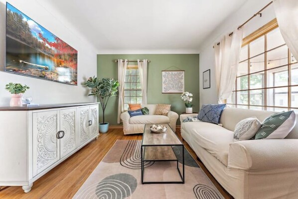A living room with a sofa, a coffee table, a cabinet, and a painting on the wall. - The Stillwater Retreat (Stillwater)