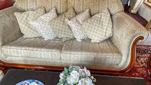 Un canapé beige à motifs, agrémenté de coussins assortis, un vase à fleurs posé sur une table et un tapis à motifs.