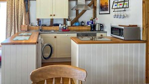 Une cuisine compacte dotée de plans de travail en bois, d’un four à micro-ondes et d’un lave-linge.