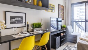 A modern living room with a dining area, featuring a TV, a sofa, a dining table with yellow chairs, and a balcony with a view. - Aurora Paulistana  (São Paulo)