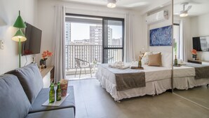 A modern hotel room with a balcony, a bed, a sofa, a TV, and a dining area. - Aurora Paulistana  (São Paulo)