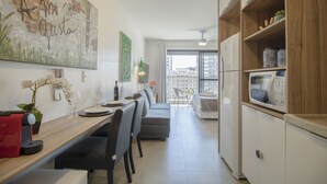 A modern kitchen with a dining area, a large painting on the wall, and a view of the city through the window. - Aurora Paulistana  (São Paulo)