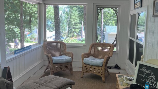 A sunroom with wicker chairs, a cushioned bench, and a table with an iPod. - The Bluebird Cottage.  Just go down 400 feet and jump in lake . (Roscommon)