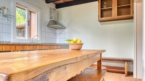A kitchen with a wooden table, a bowl of lemons, and a honeycomb cabinet.