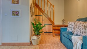 A cozy living room with a blue sofa, a wooden staircase, and a potted plant.