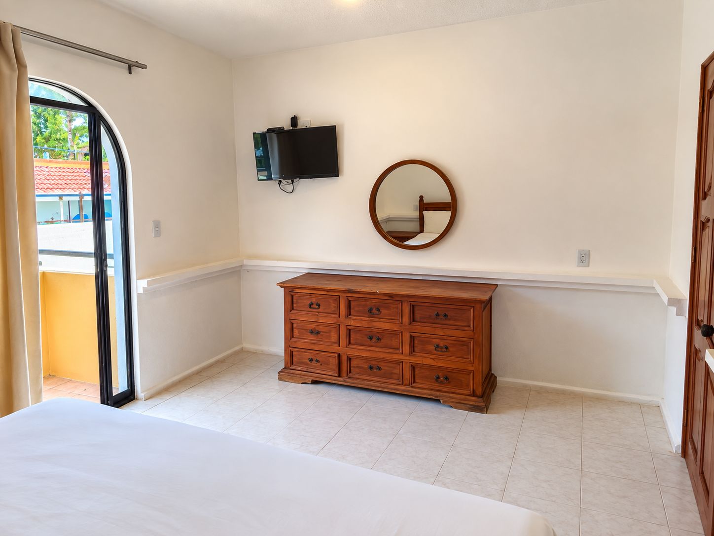 Un dormitorio con cama, cómoda, televisor y espejo.