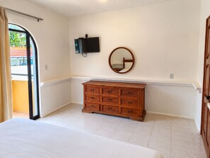 Une chambre à coucher avec un lit, une commode, un téléviseur et un miroir.