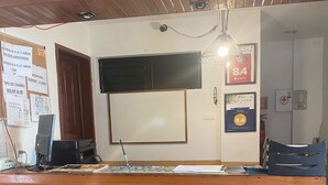Een receptiebalie met de naam 'Hotel Vuta Carive' erin gekerfd, een flatscreen televisie erboven en een ingelijst certificaat aan de muur.