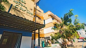 Een hotel met een bord waarop 'Hotel Vista Caribe' staat, een meerhoog gebouw met balkons, en een straat met geparkeerde auto's en bomen.