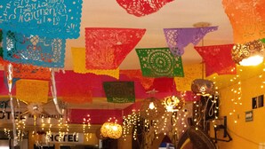 Een restaurant met gedekte tafels, versierd met kleurrijke papirsnijwerk en lichtjes.