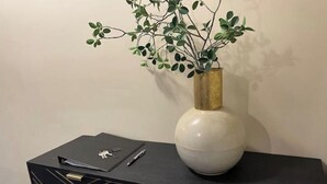 A black table with a white vase containing green foliage.