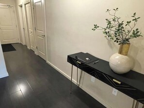Un pasillo con una consola negra, un florero blanco y una puerta al final.