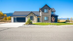 A modern two-story house with a garage, stone foundation, and a sloped roof. - Hot Tub & Deck at Red Lodge Retreat (Red Lodge)