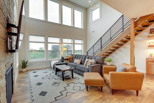 A spacious living room with a large window, a staircase, and a cozy seating area. - Hot Tub & Deck at Red Lodge Retreat (Red Lodge)