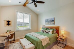 A bedroom with a bed, a desk, a chair, a ceiling fan, a window, and a nightstand with a lamp. - Hot Tub & Deck at Red Lodge Retreat (Red Lodge)