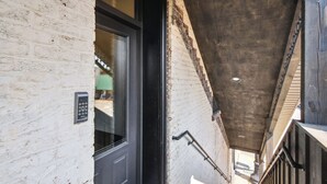 Una escalera estrecha con una pared de ladrillo blanco y una puerta negra.