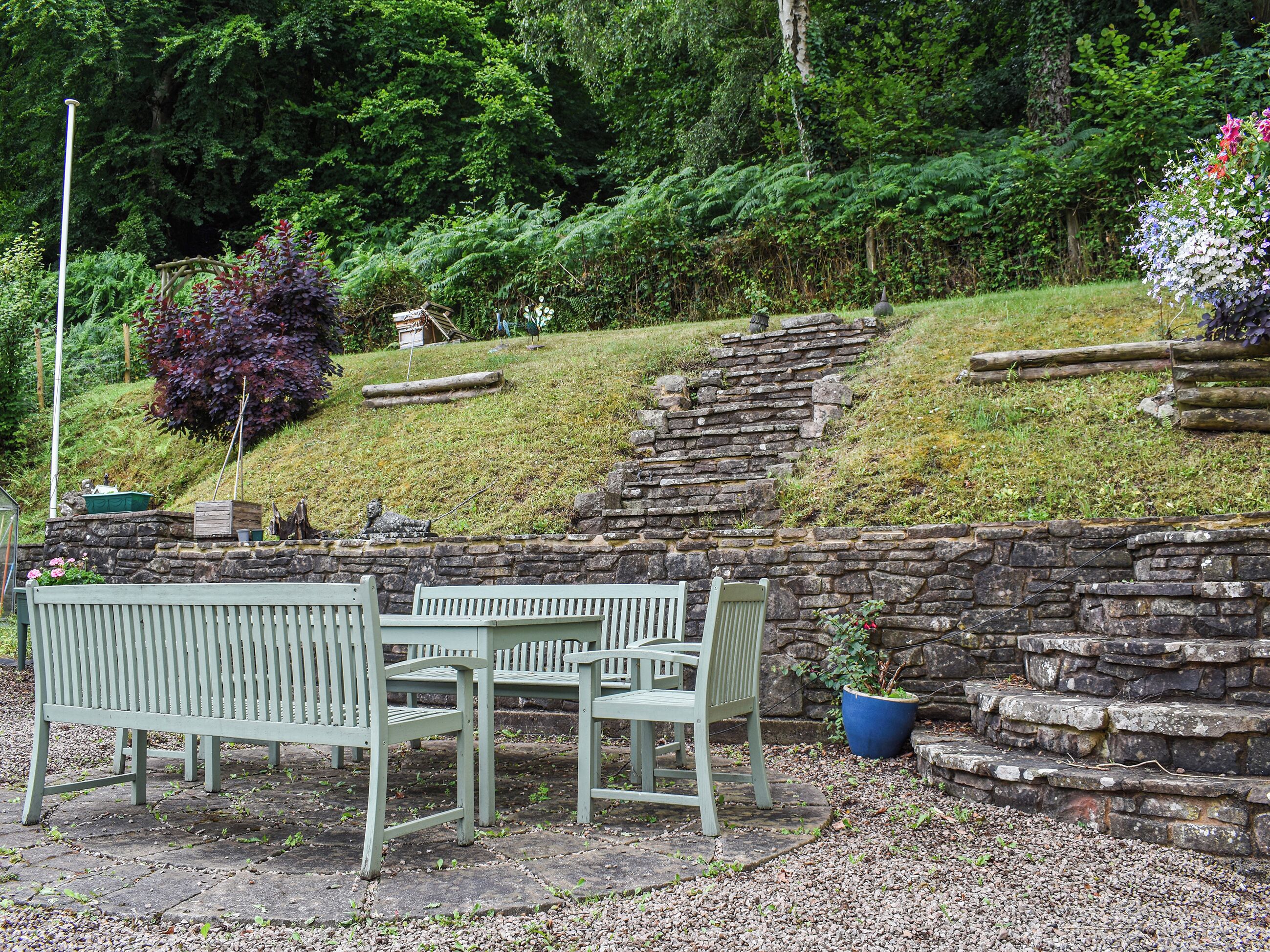 A stone wall with a bench and a table in a garden setting.
