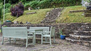 Eine Steinsitzmauer mit Bank und Tisch in einem Garten.