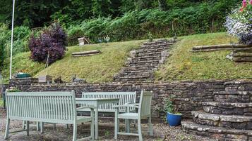A stone wall with a bench and a table in a garden setting.