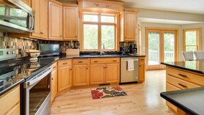 A modern kitchen with wooden cabinets, stainless steel appliances, and a large window. - Riverfront Bliss in Rice Lake: Deck, Grill & Hike! (Rice Lake)