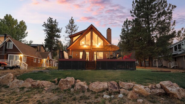 A lodge with a prominent wooden structure, a porch, and a fenced yard with rocks. - 3 Cubs Lakefront Cabin  (Big Bear Lake)