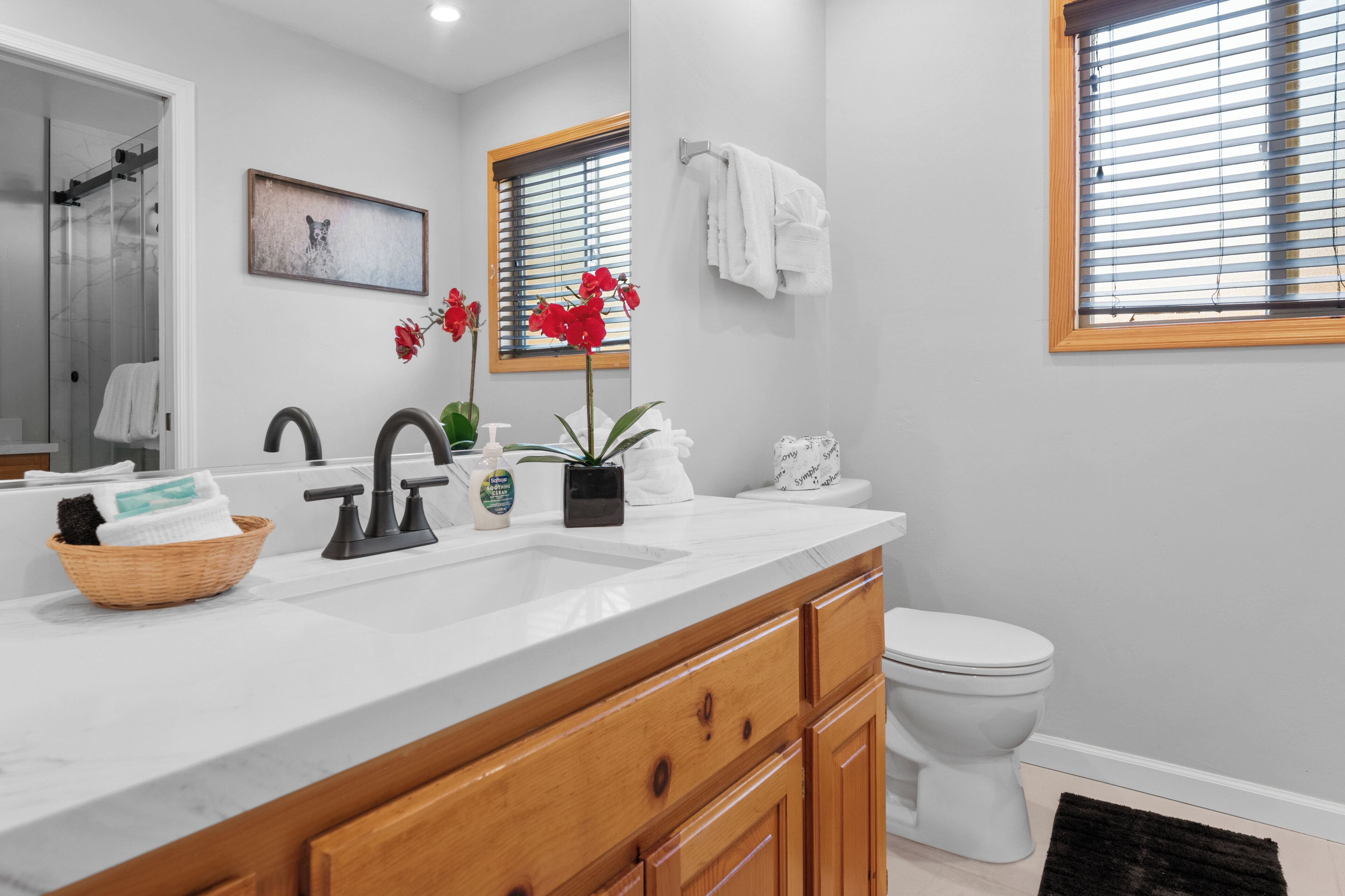 Une salle de bain moderne avec un lavabo blanc, des meubles en bois, des toilettes et un espace douche.