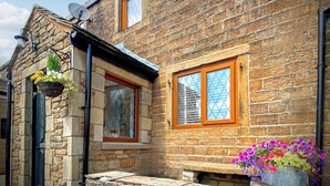 Un bâtiment en pierre avec une porte en bois, une fenêtre avec un cadre en bois et une antenne parabolique sur le toit.