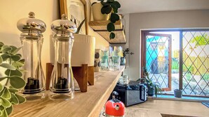 Un plan de travail de cuisine avec une bouilloire, une machine à café et un grille-pain. On y trouve également des récipients en verre et une plante.