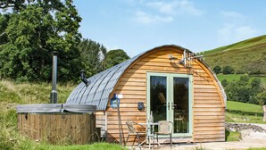 A wooden cabin with a sloped roof, a glass door, and a small patio area with outdoor furniture.