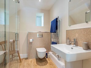 Un baño moderno con cabina de ducha de vidrio, inodoro, bañera y lavamanos.