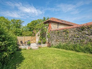 A stone wall, a wooden gate, and a patio with a table and chairs.