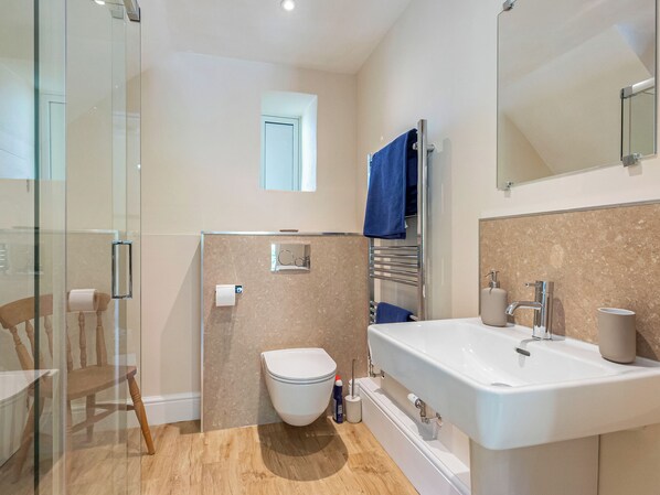 A modern bathroom with a glass shower enclosure, a toilet, a bathtub, and a sink.