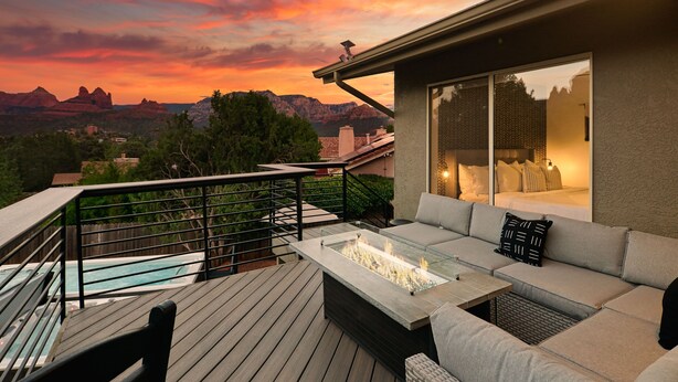 En terrasse med et bord med glasplade, udendørs sofa og et spabad.