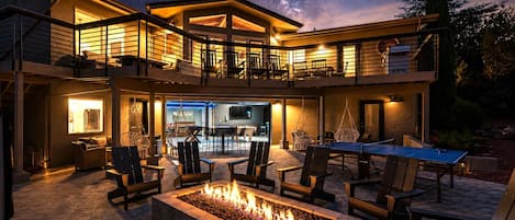 Una casa moderna con una chimenea exterior, zona de estar al aire libre y un área de piscina.