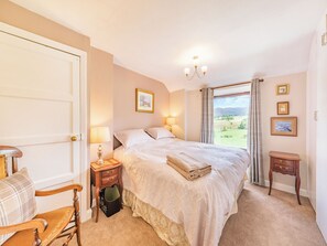 A bedroom with a bed, bedside tables, a chair, a window with a view, and a chandelier. - 3 bedroom accommodation in Brampton, near Appleby-in-Westmorland (Brampton, near Appleby-in-Westmorland)