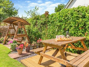 A wooden swing set, a picnic table with bread and a lantern, and potted flowers in a garden. - 3 bedroom accommodation in Brampton, near Appleby-in-Westmorland (Brampton, near Appleby-in-Westmorland)