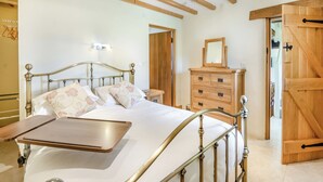 Ein Schlafzimmer mit einem Bett, einem Nachttisch, einer Holzkommode und einer Holztür.