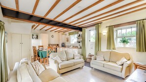 Ein geräumiges Wohnzimmer mit zwei Sofas, einem Essbereich mit Tisch und Stühlen und einer Küche im Hintergrund.