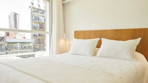 Hotellihuone, jossa on suuri sänky, puinen pääty ja suuri ikkuna, josta avautuu näkymä kaupunkiin.