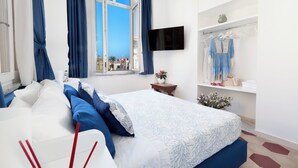 A modern hotel room with a large bed, a TV mounted on the wall, and a view of the city through the window. - shinehouse (Sorrento)