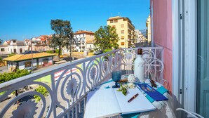 A balcony with a table set for dining, overlooking a cityscape with buildings and trees. - shinehouse (Sorrento)