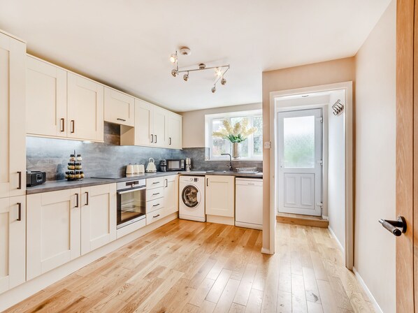 A modern kitchen with white cabinets, a built-in oven, microwave, and dishwasher.