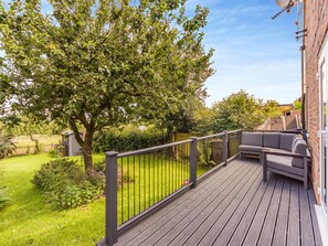 A wooden deck with a metal railing, a built-in sofa, and a tree in the background. - Wheelwright's Cottage (Rodsley, near Ashbourne)