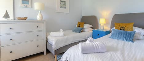 A hotel room with two beds, a dresser, a nightstand, and a mirror.