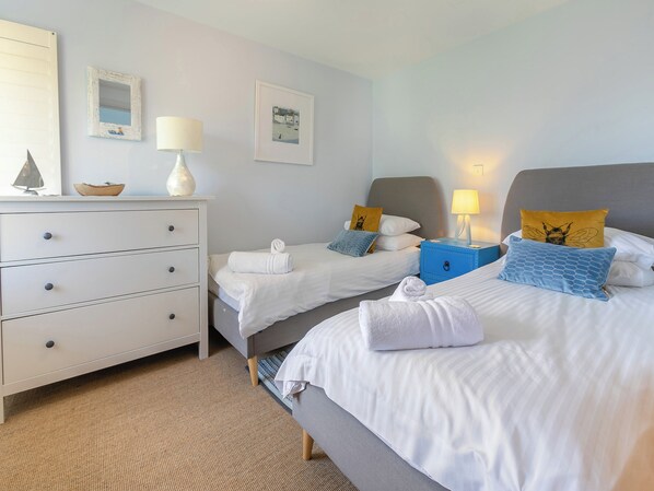A hotel room with two beds, a dresser, a nightstand, and a mirror.
