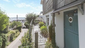 A narrow street with a building on the right, a green door, and a view of the sea in the background. - 4 bedroom accommodation in St. Mawes (St. Mawes)